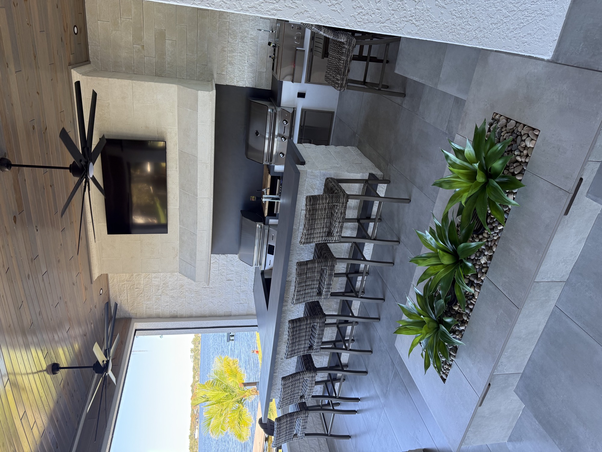 The covered lanai with mounted TV, bar seating, and lit planter wall in the evening