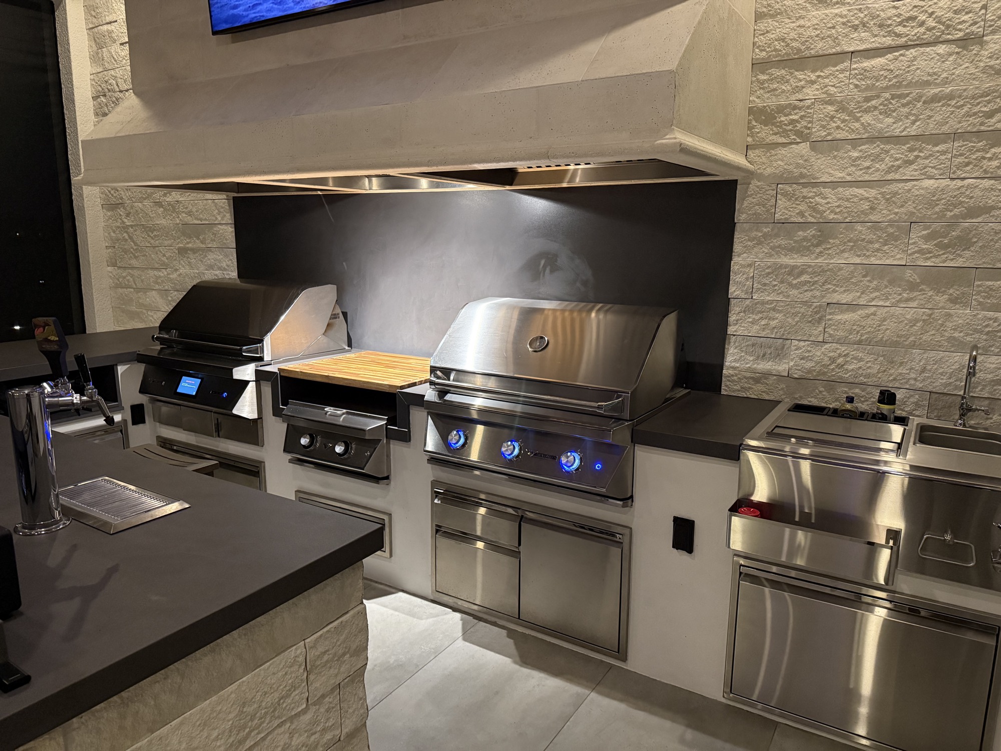 The grill, power burner, and pellet smoker set under the precast hood in Apopka, FL