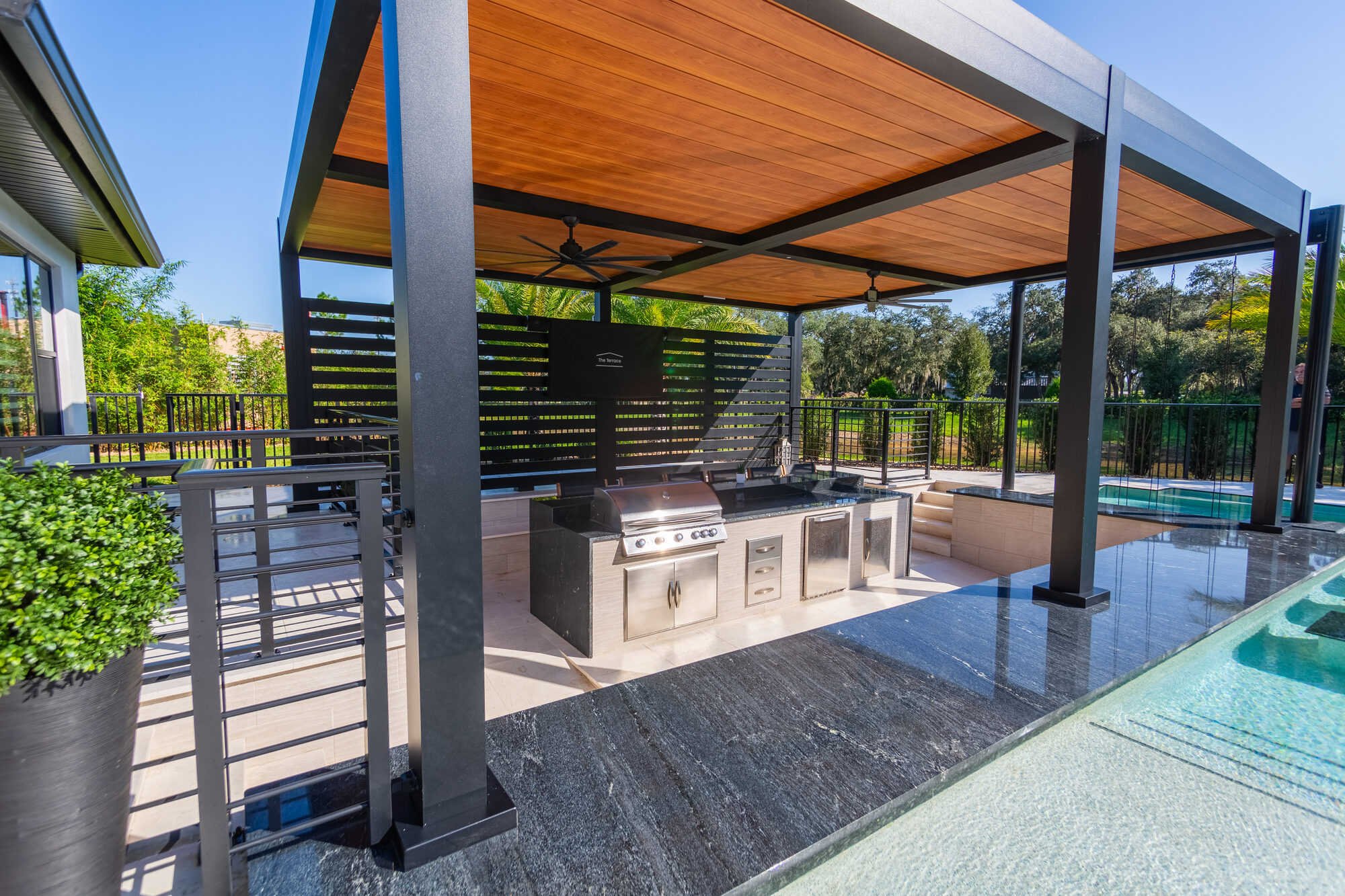 Adjustable louvered roof with a wood-tone finish over the pool patio