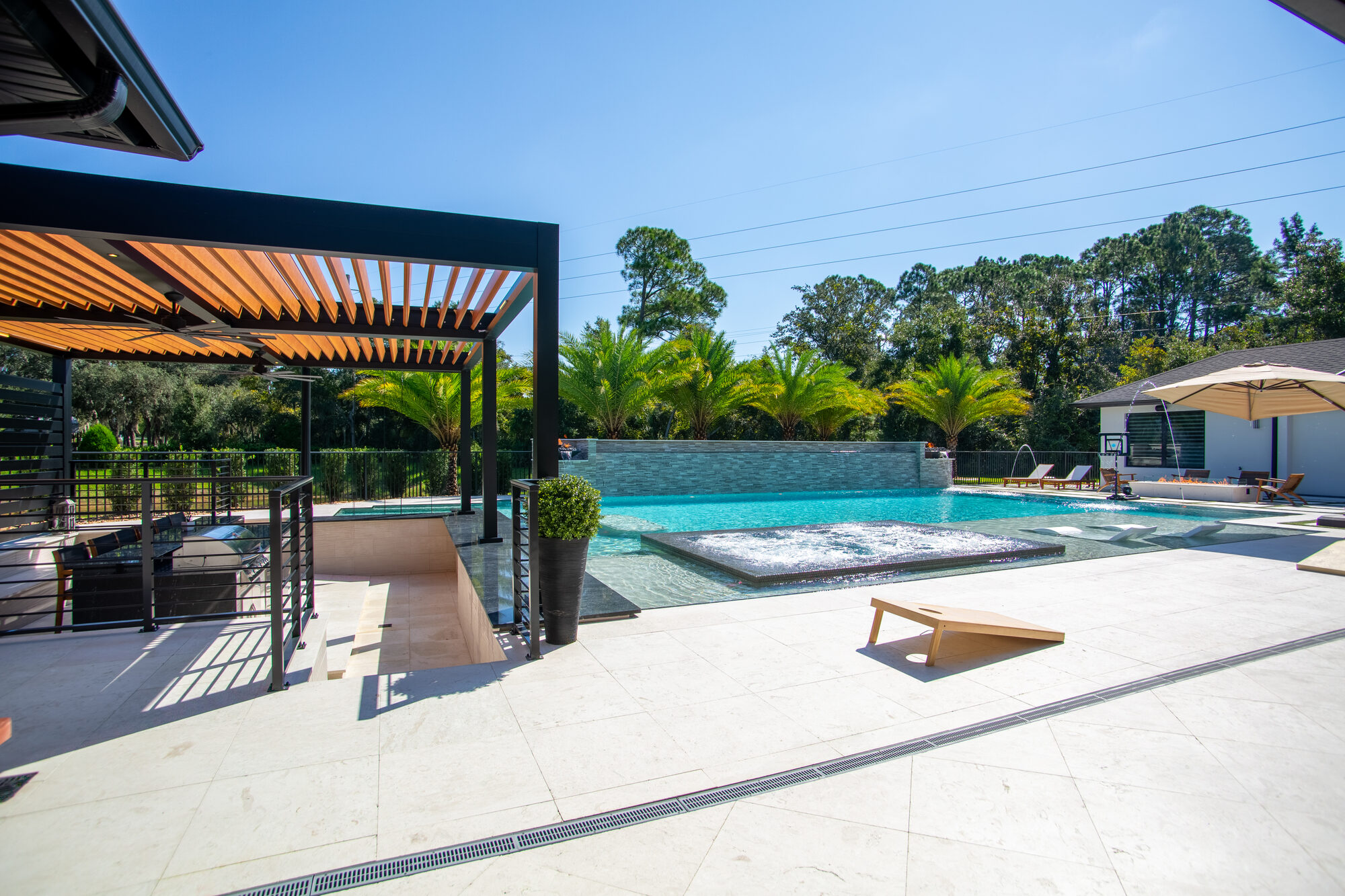 Wood-tone louvers on the black aluminum pergola roof over the pool